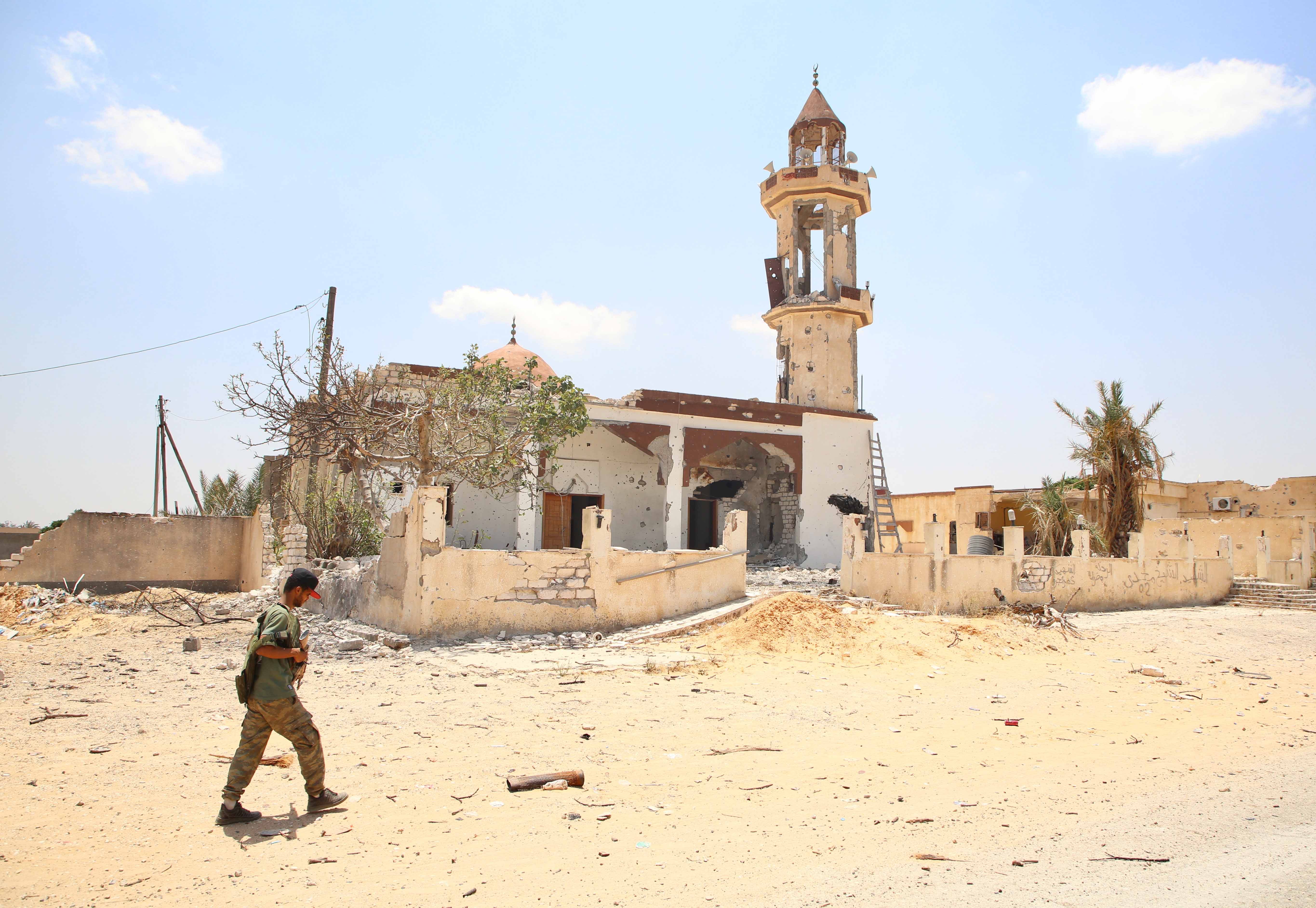 Un homme marche devant une mosquée endommagée lors de récents combats entre des forces rivales, au sud de Tripoli, la capitale de la Libye, le 2 juin 2020.