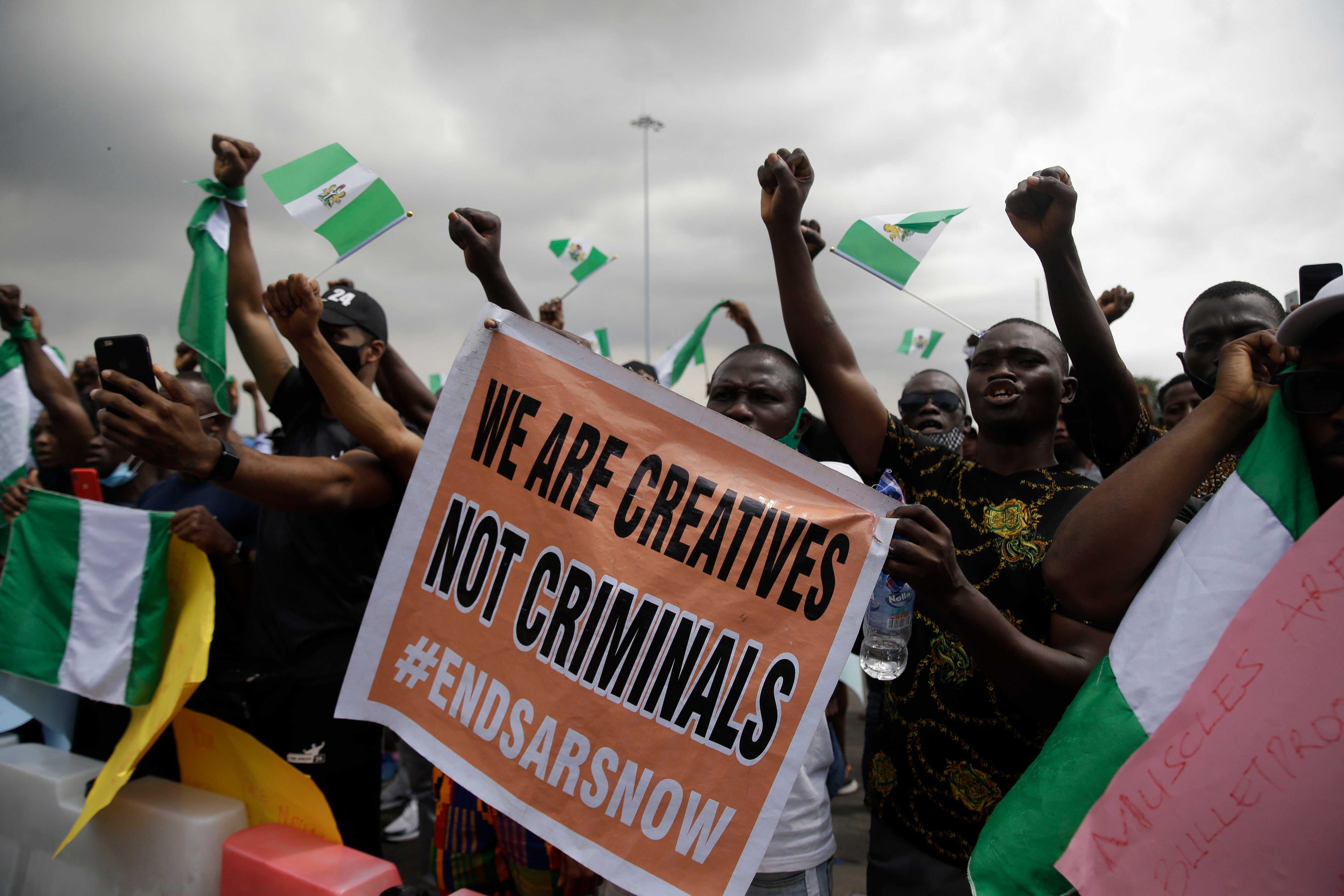 People hold banners and flags as they protest against police brutality in Lagos, Nigeria, Monday Oct. 19, 2020. 