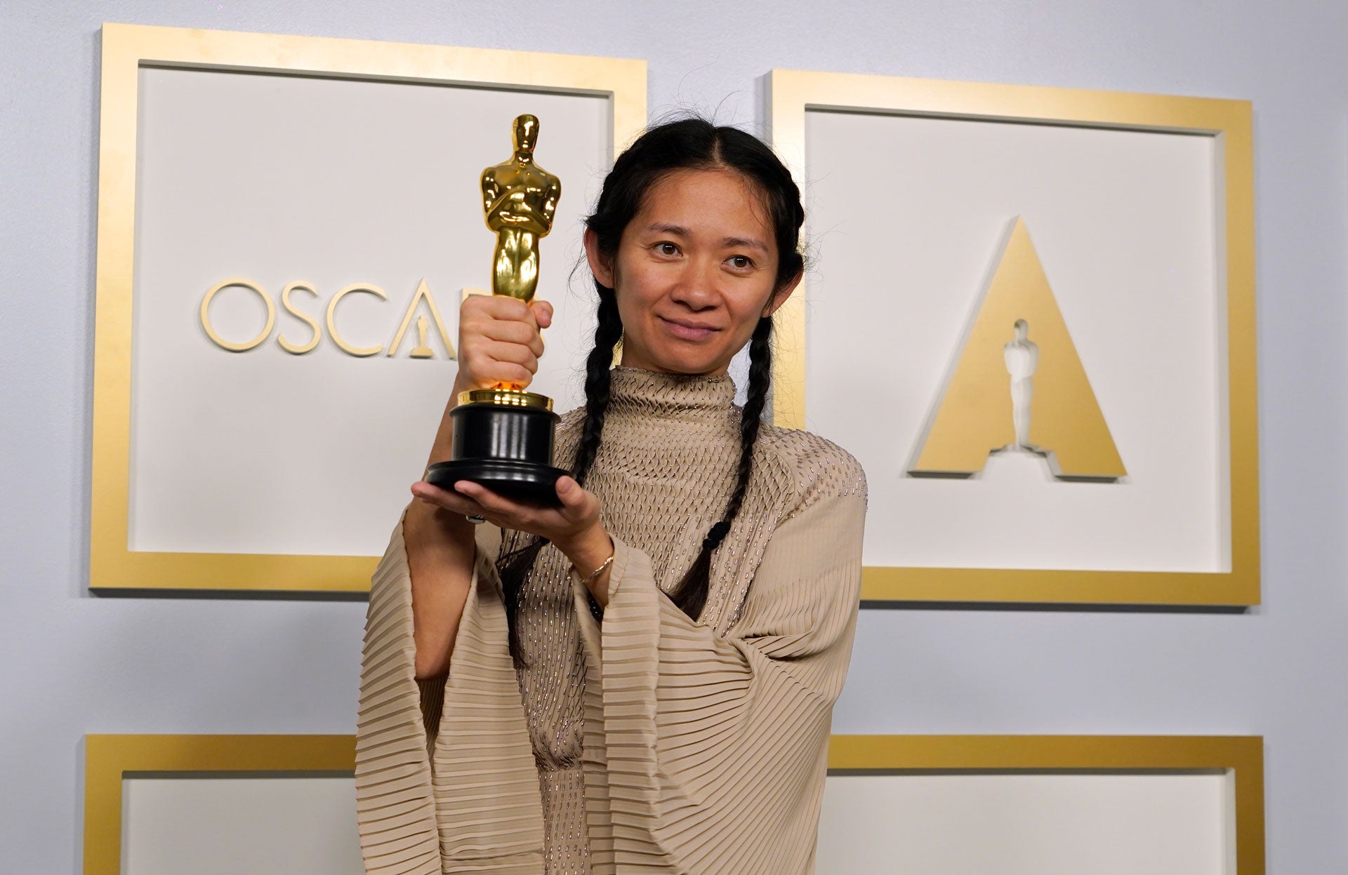 Director Chloe Zhao smiles and holds her golden Oscars statue after winning the award for Best Director