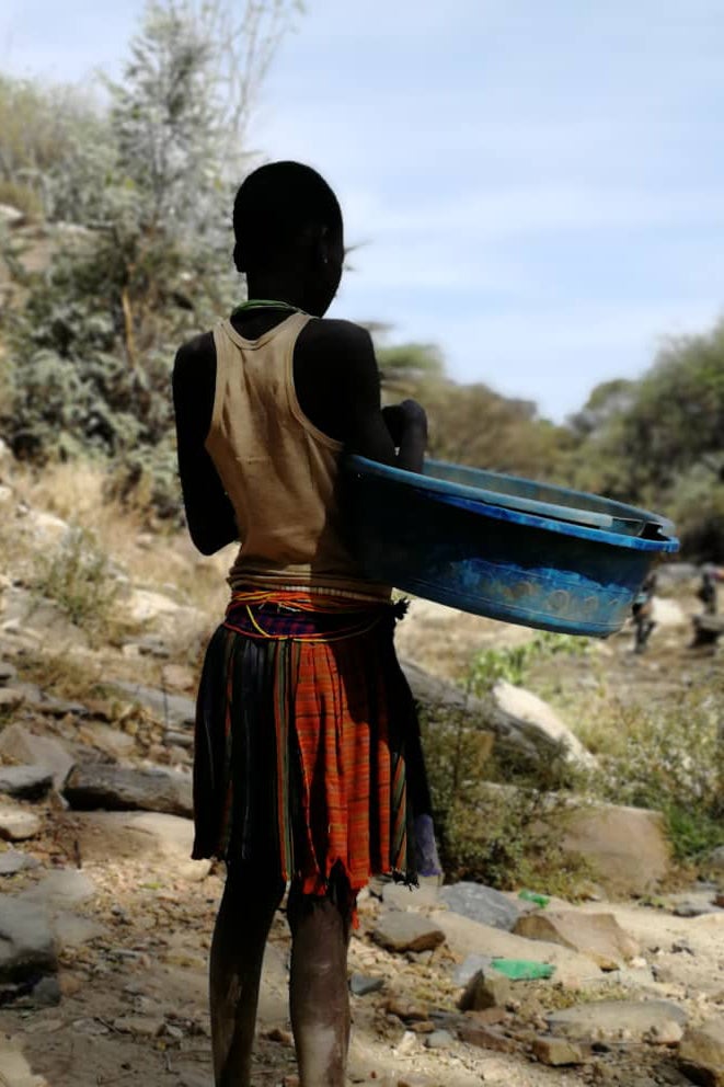 A girl holds a large pan at a mining site