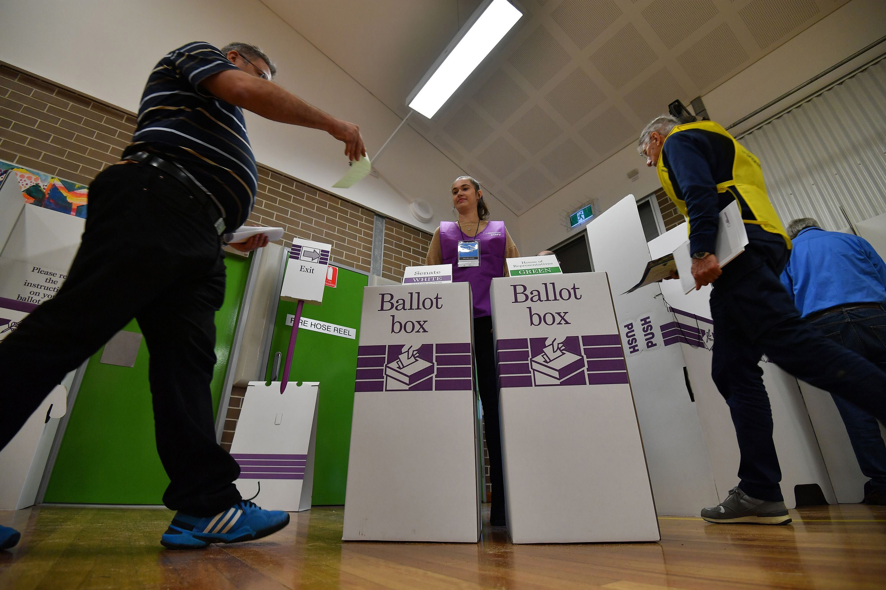 A voter drops his ballot paper into the ballot box during Australia's general election in Sydney.