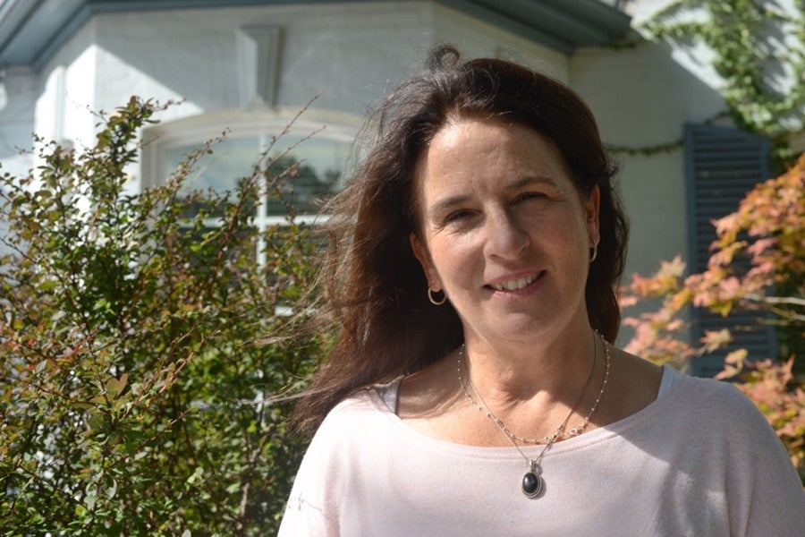 A woman stands outside during the day looking at the camera