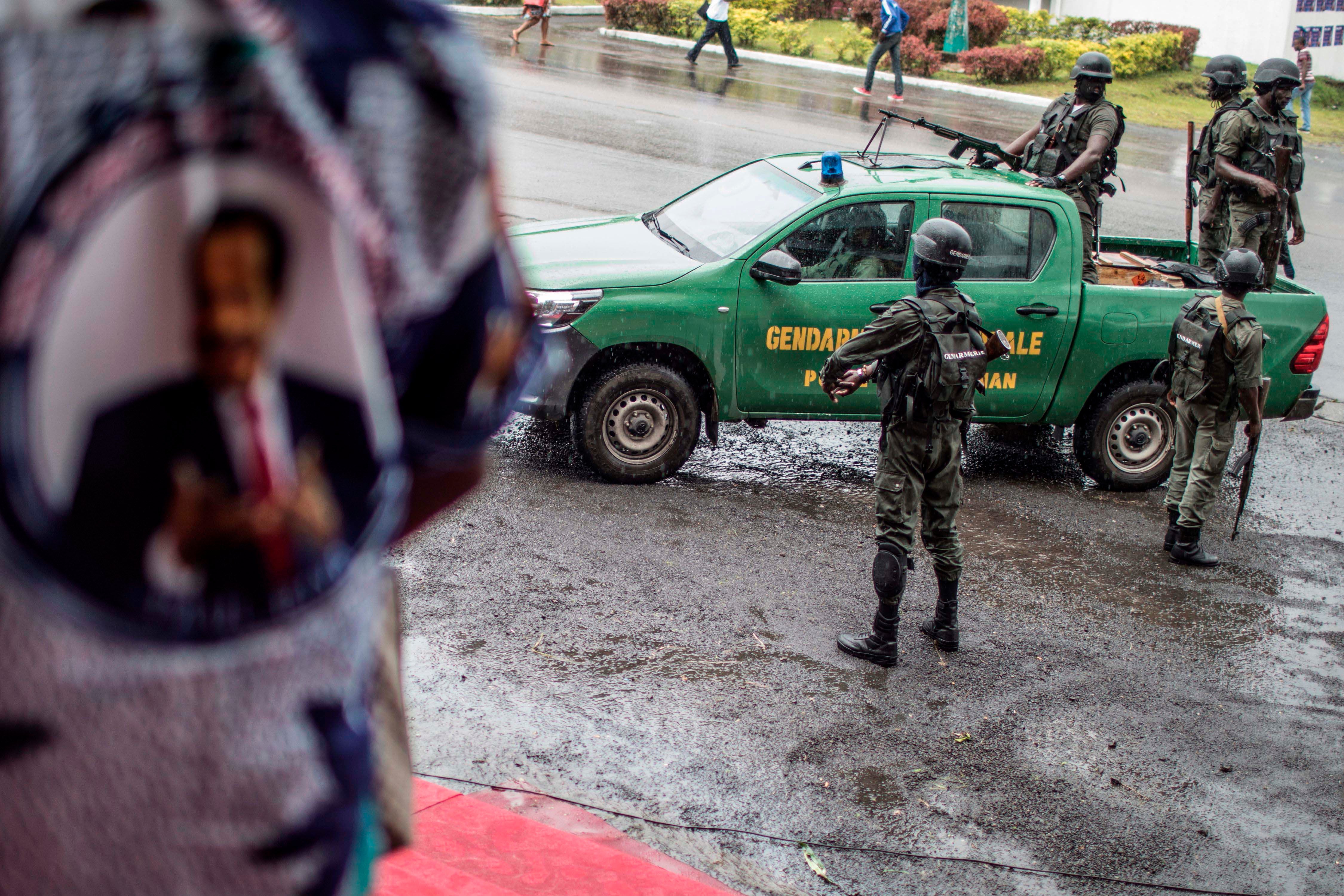 Uniformed officers stand near a police vehicle 