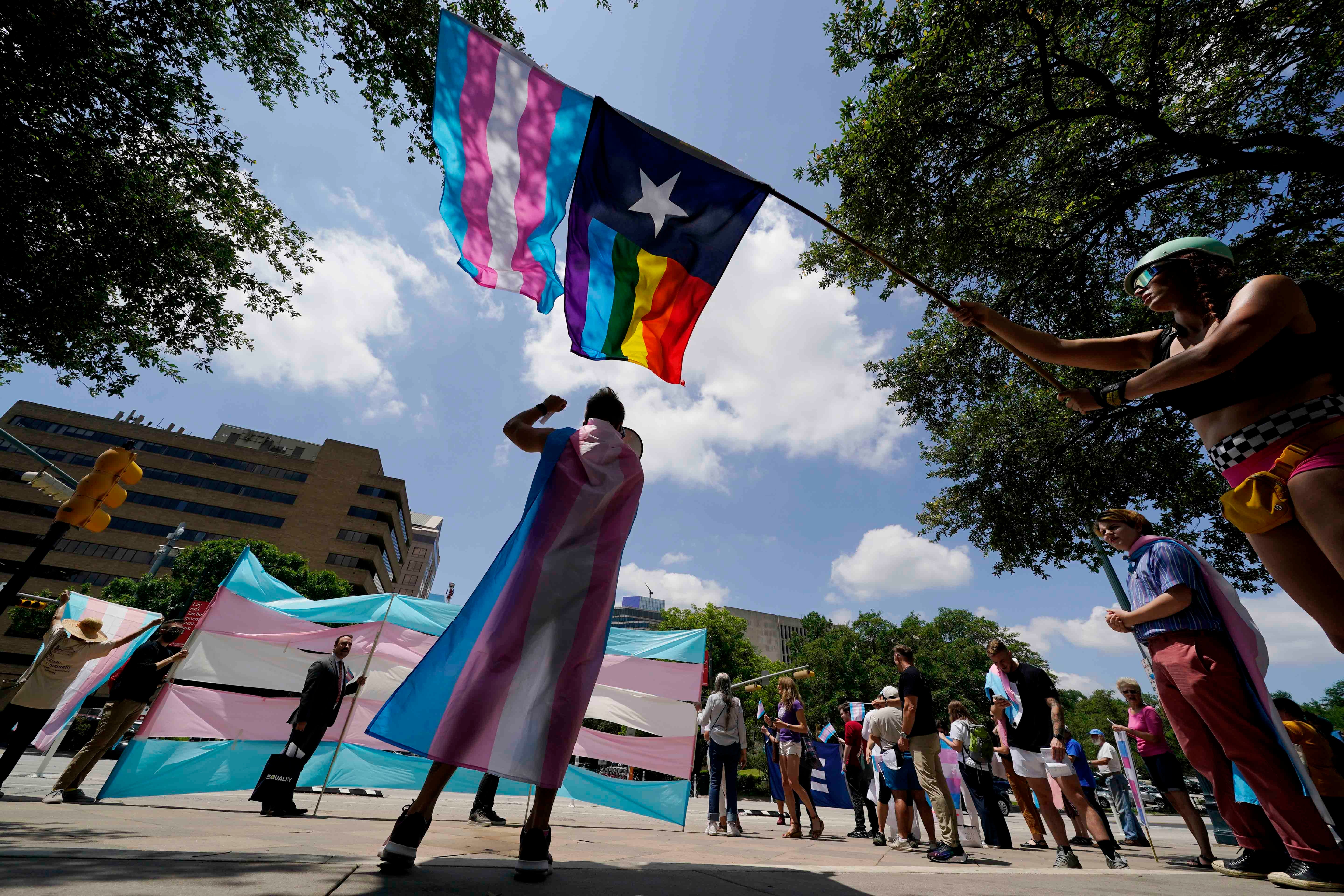 Protesters waving trans and lgbtq pride flags