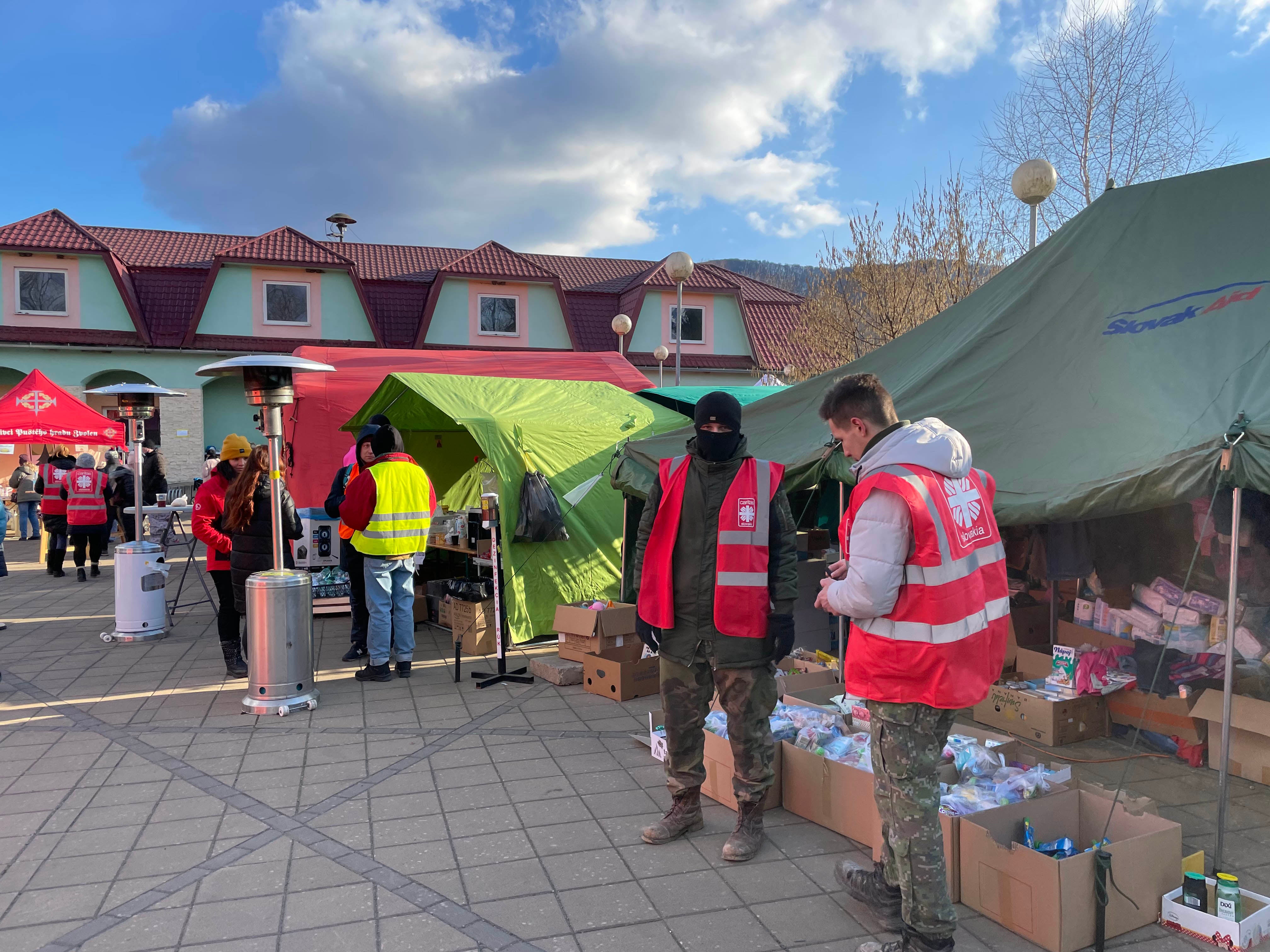 Officials in vests stand near a tent