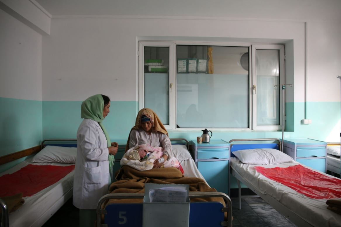 A woman in a hospital bed holds a newborn baby.
