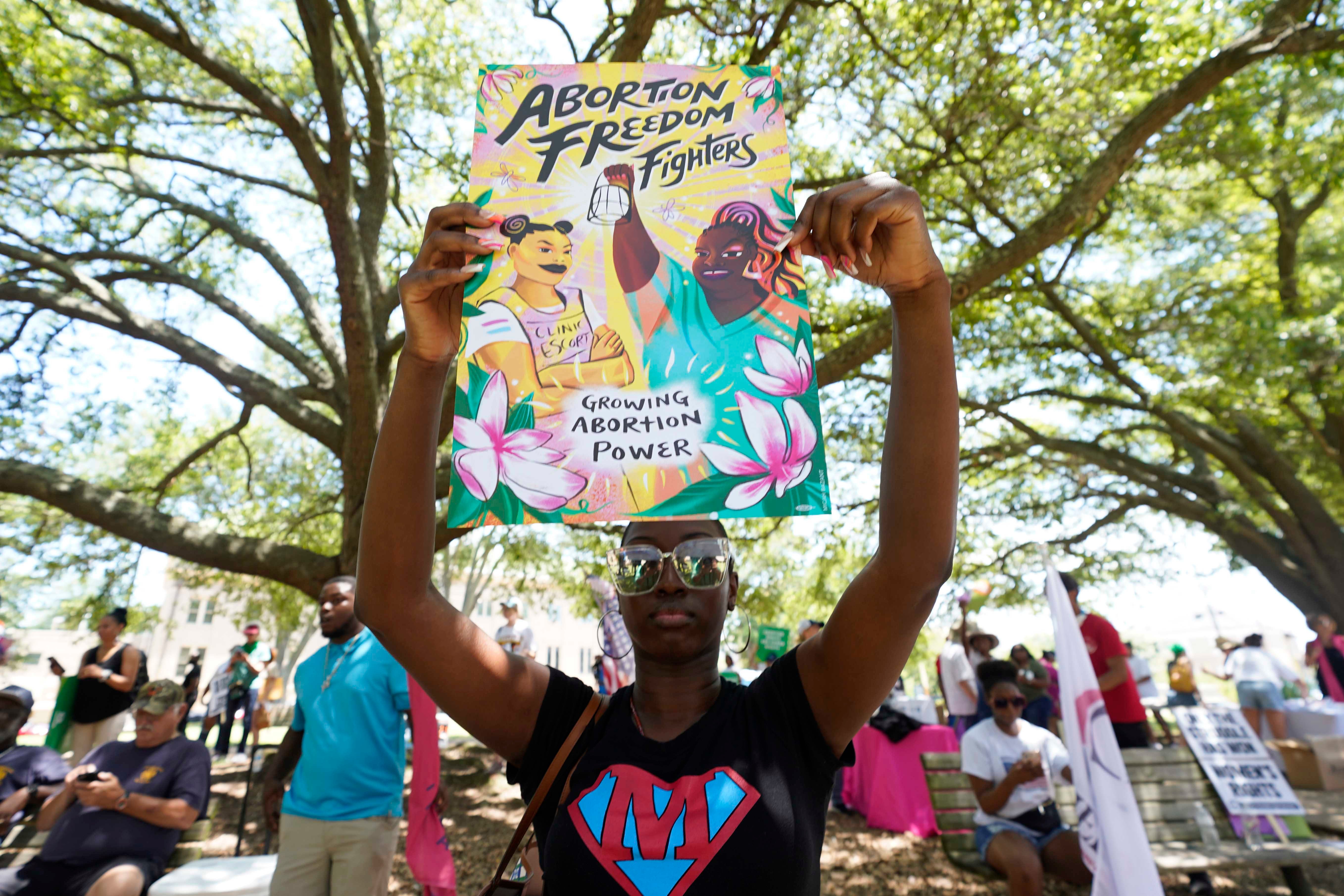 A protester holds a sign that reads "Abortion Freedom Fighters" and "Growing Abortion Power"