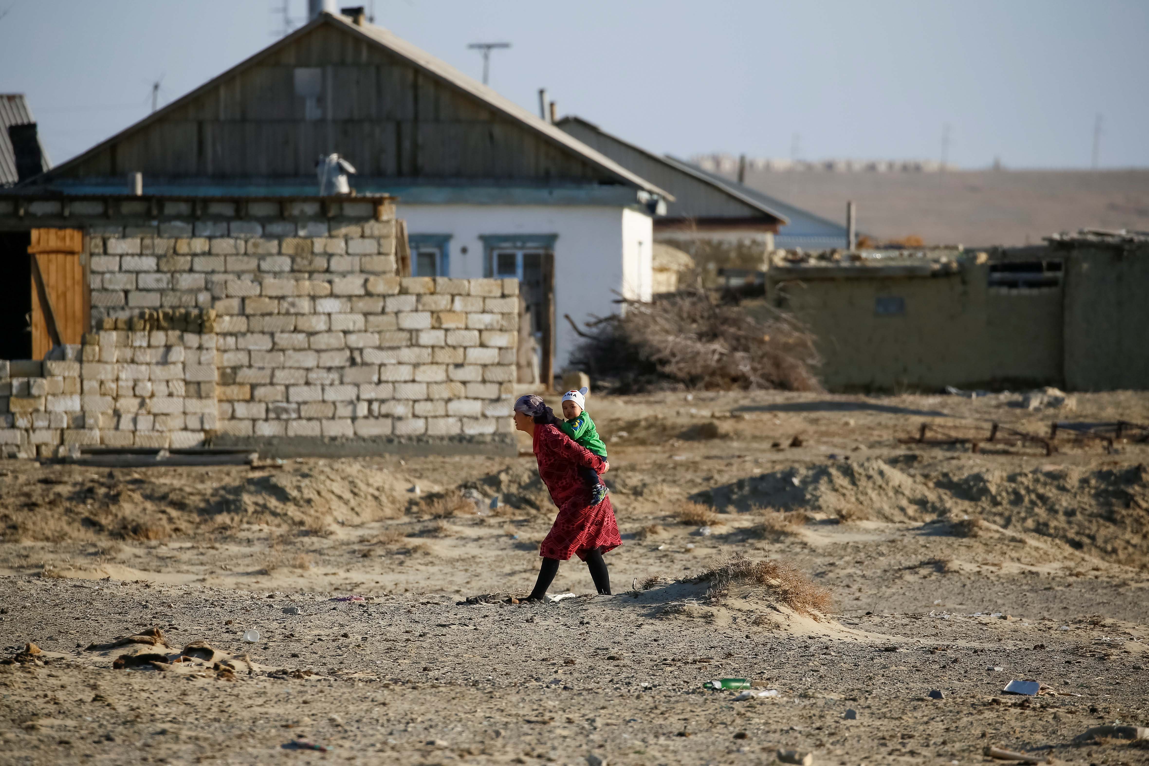 A woman carries a child in the village of Zhalanash, Kazakhstan, April 16, 2017.