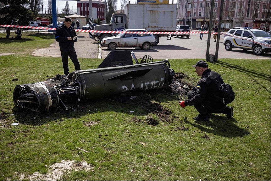 Deux experts travaillant pour les autorités ukrainiennes inspectaient le moteur-fusée et la section de guidage d'un missile Tochka-U près du bâtiment principal de la gare de Kramatorsk, dans l'est de l'Ukraine, le 8 avril 2022. Les mots russes peints en blanc sur le missile signifient « Représailles pour les enfants ».