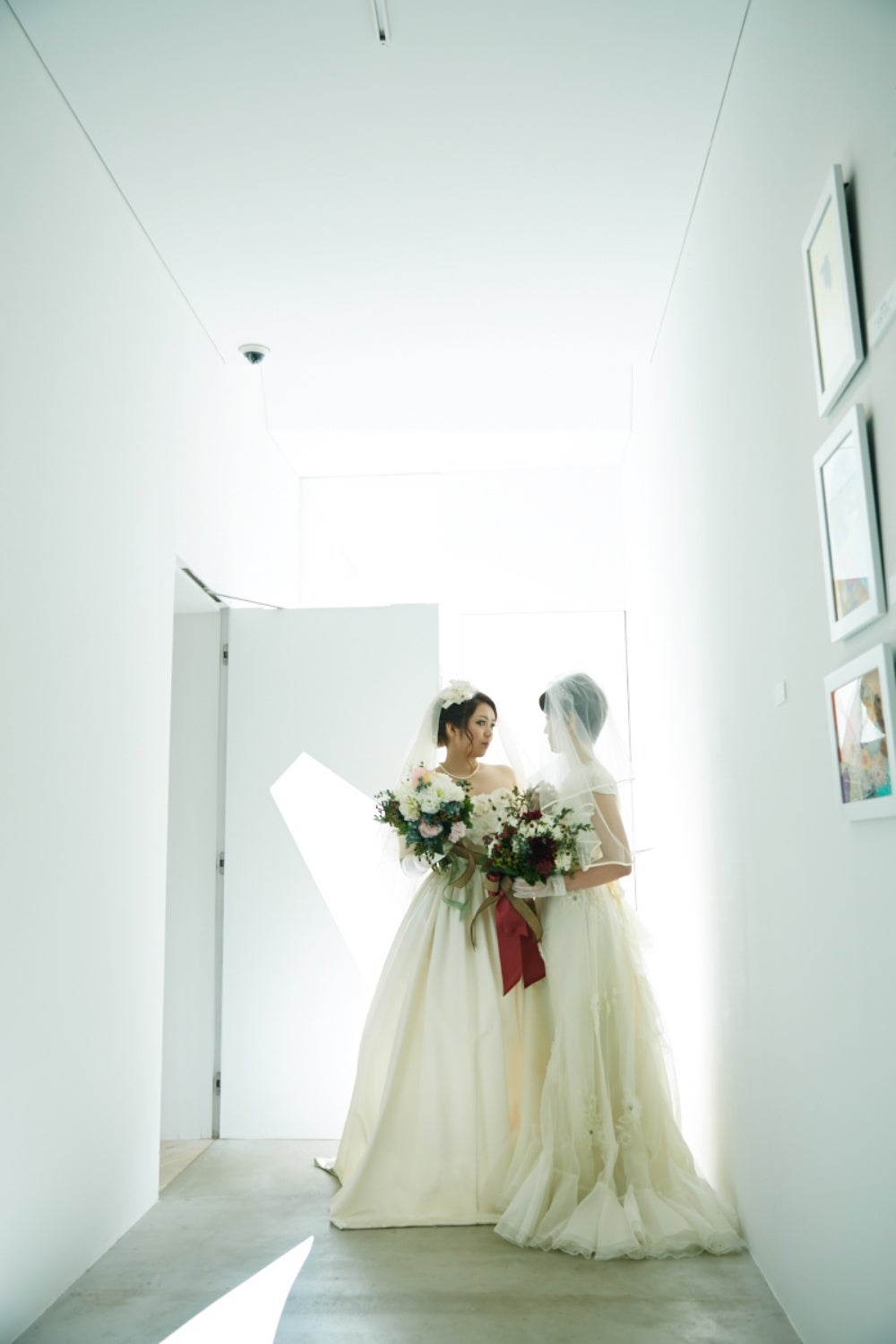 Two women pose for a photo in wedding dresses