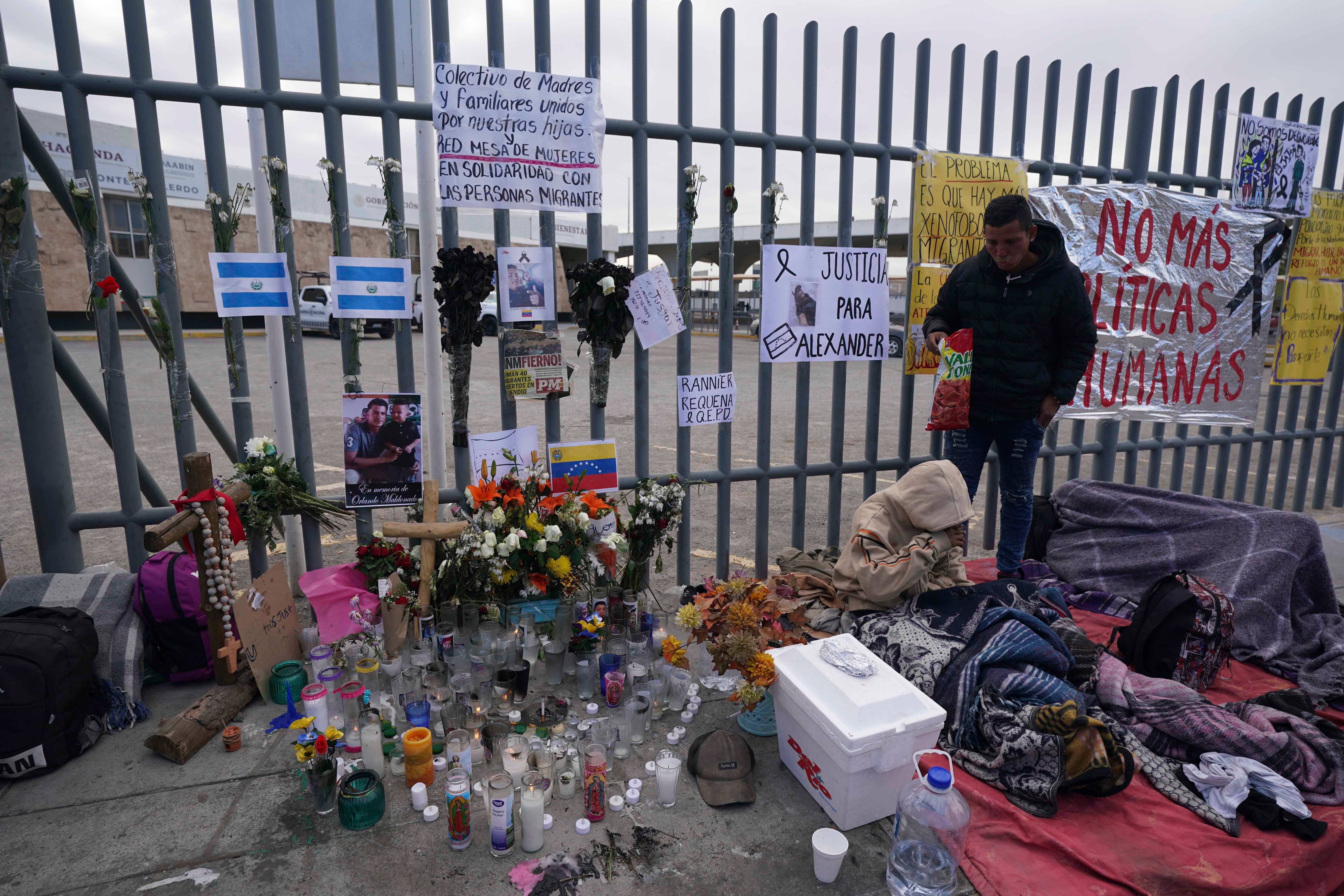 An altar with candles and photos covers the fence outside a Mexican immigration detention center