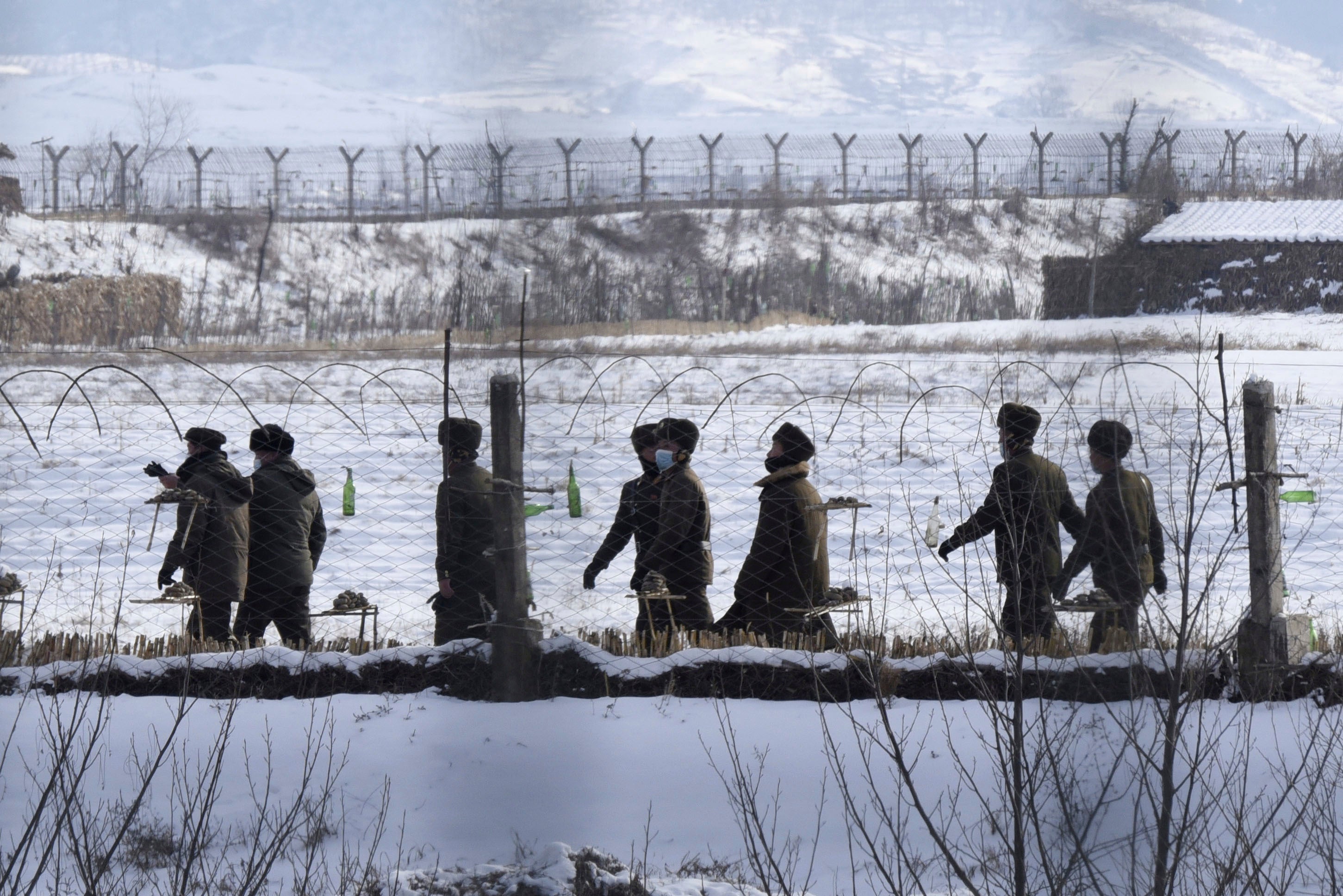 Des soldats nord-coréens patrouillaient au bord d'une rivière dans le comté d'Uiju, près de la frontière avec la Chine, le 22 décembre 2022 ; photo prise à Dandong, ville frontalière sur le territoire chinois.