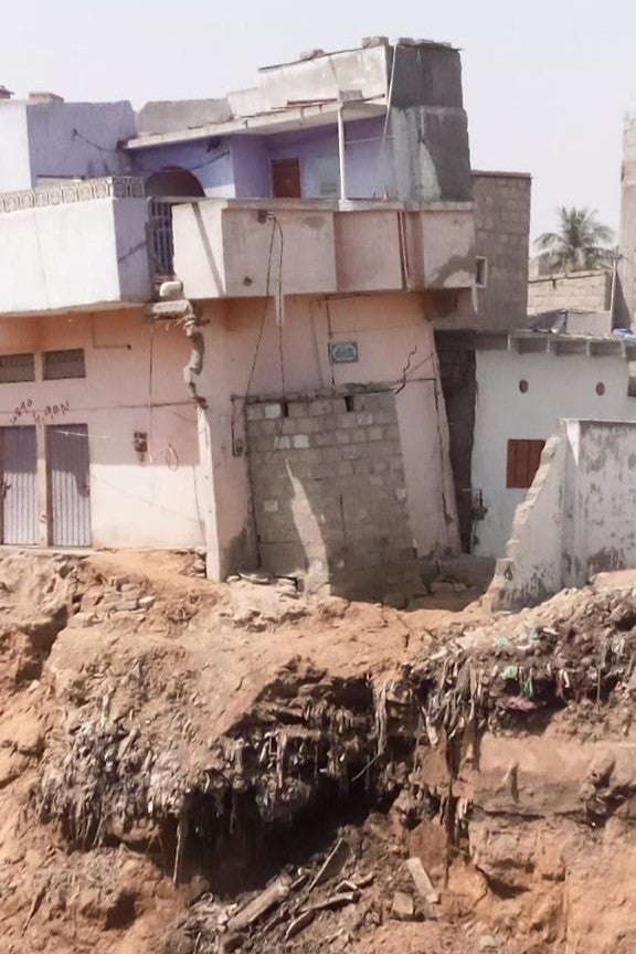 A house dangerously tilted due to landslides caused by excessive digging near a portion of a stormwater channel
