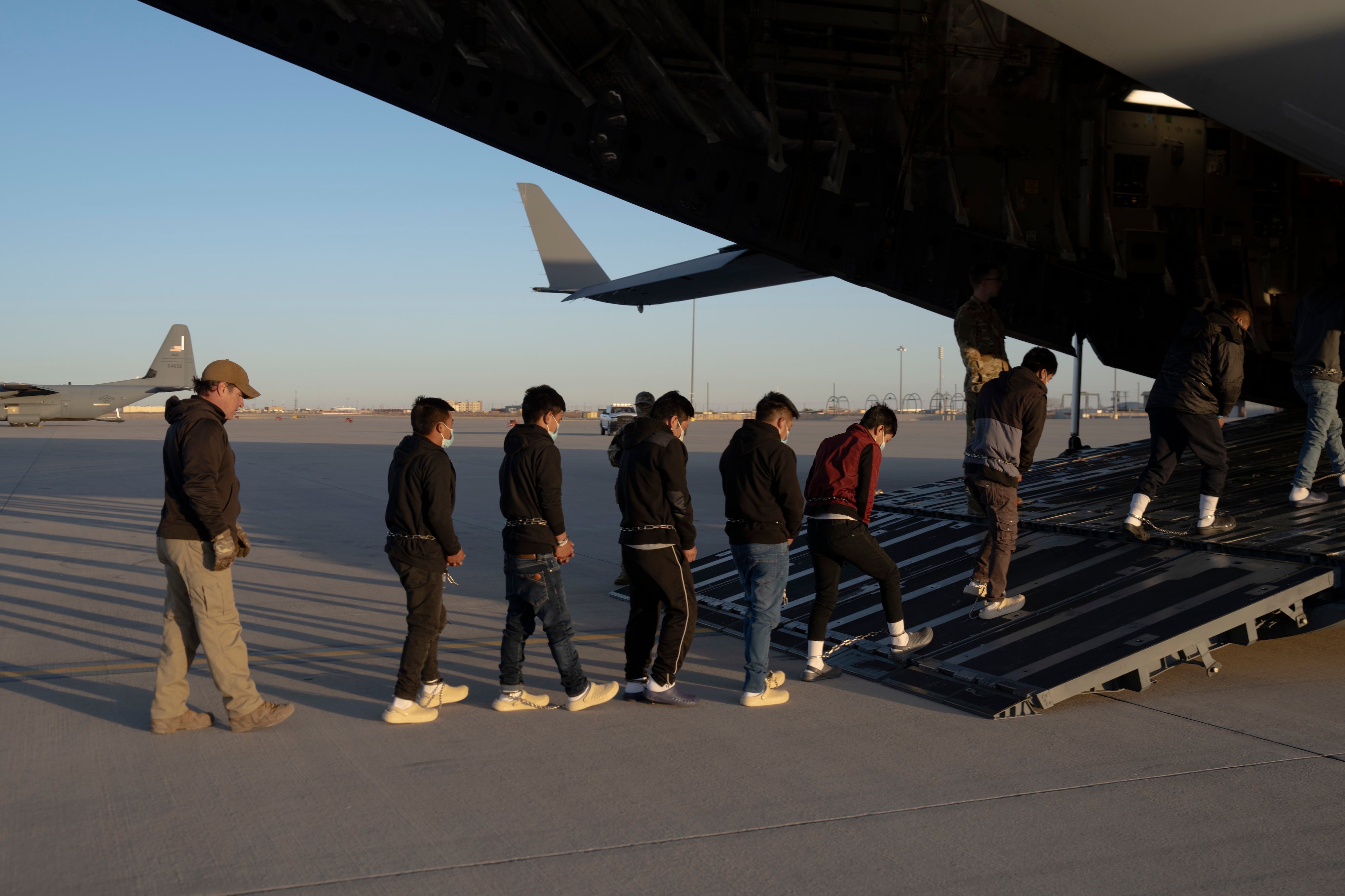 US Customs and Border Protection security agents guide people onboard a C-17 Globemaster III for a removal flight at Fort Bliss, Texas, January 23, 2025. 