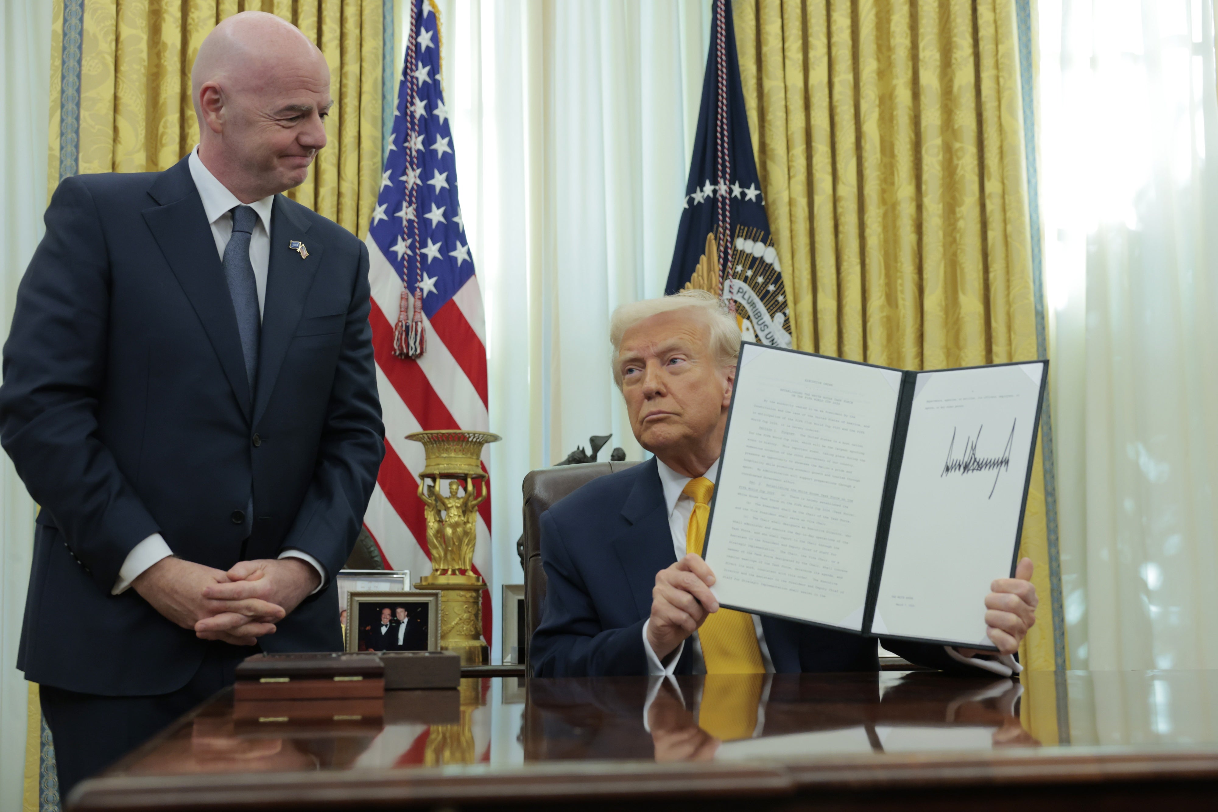 El presidente de Estados Unidos, Donald Trump, muestra una orden ejecutiva junto al presidente de la Federación Internacional de Fútbol Asociación (FIFA), Gianni Infantino, en la Oficina Oval de la Casa Blanca en Washington, DC, el 7 de marzo de 2025.