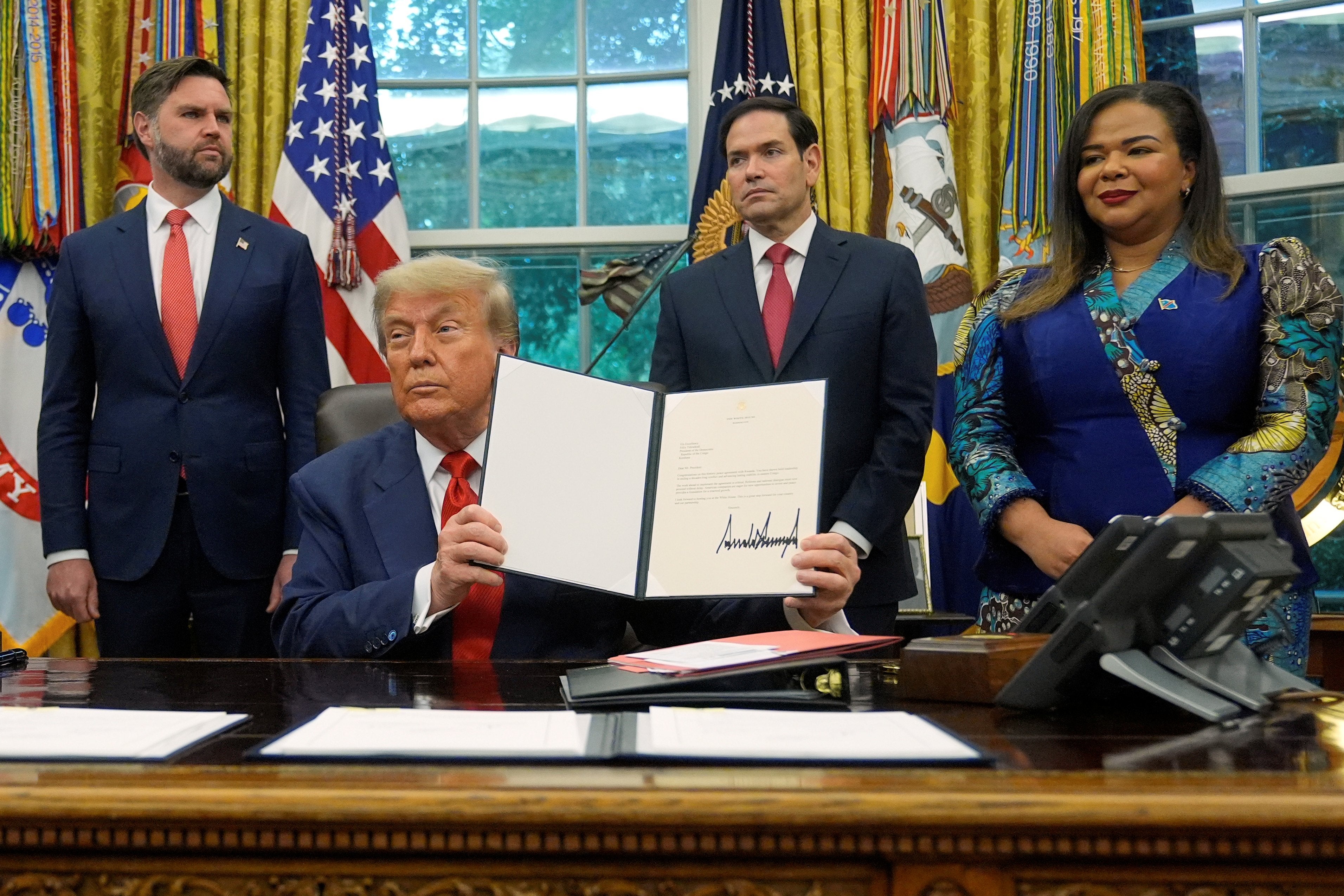 Trump holds up a signed document of the Rwanda DRC deal.