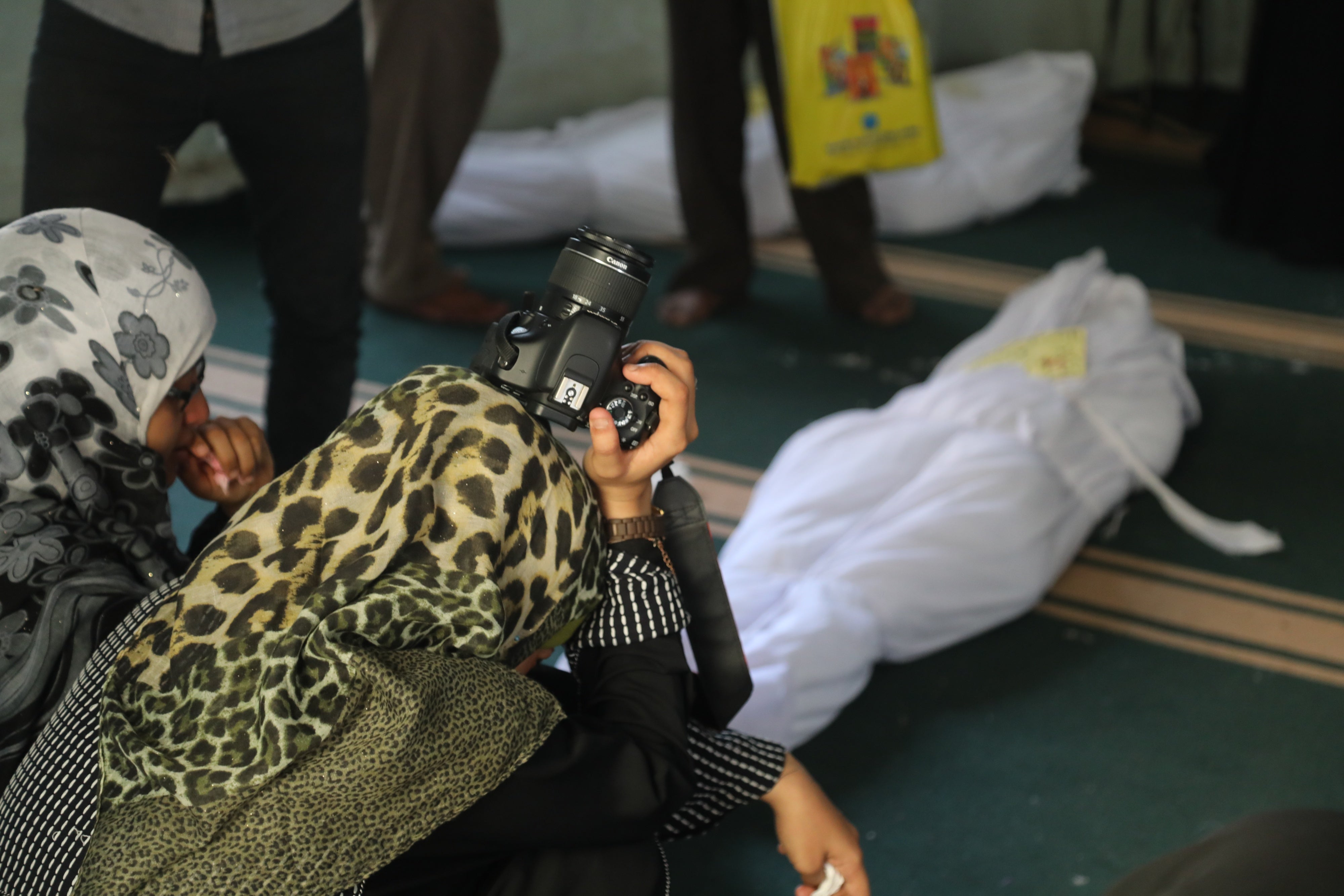 Two women mourning in front of a covered body