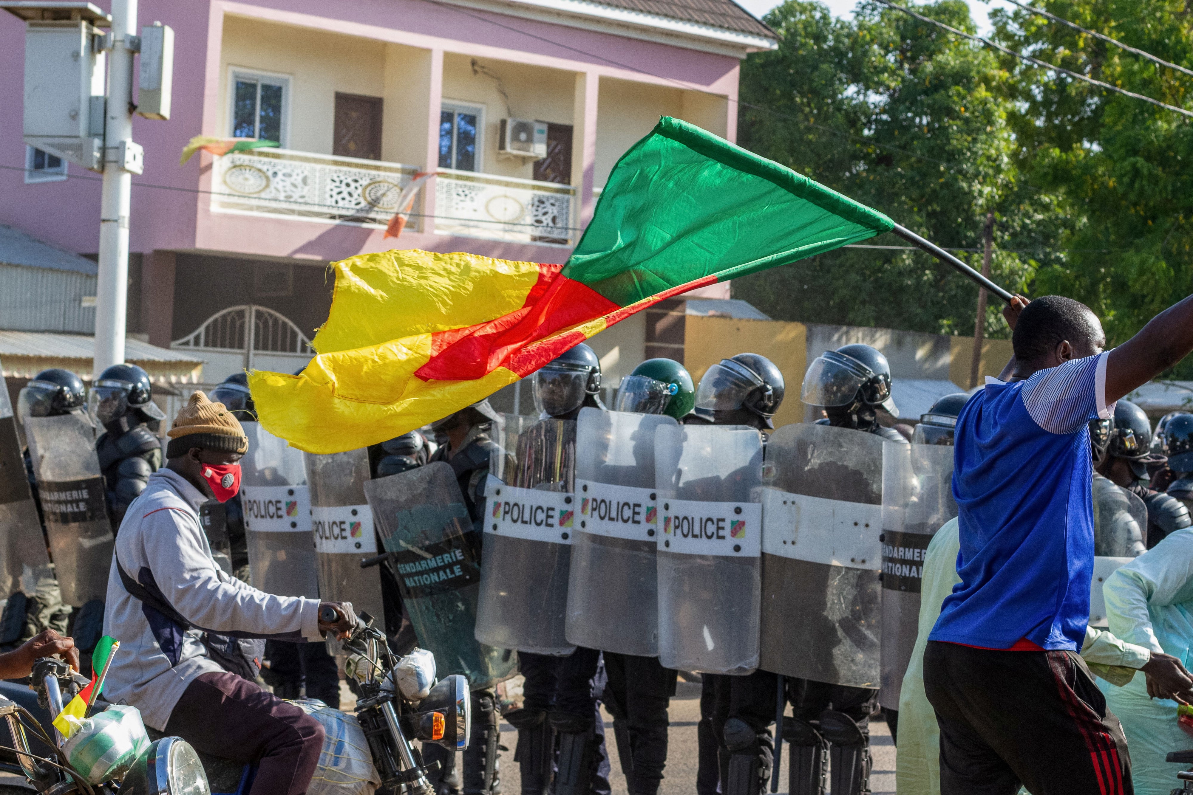 A protester waving a Cameroonian flag approaches police officers as they gather in Garoua on October 26, 2025.