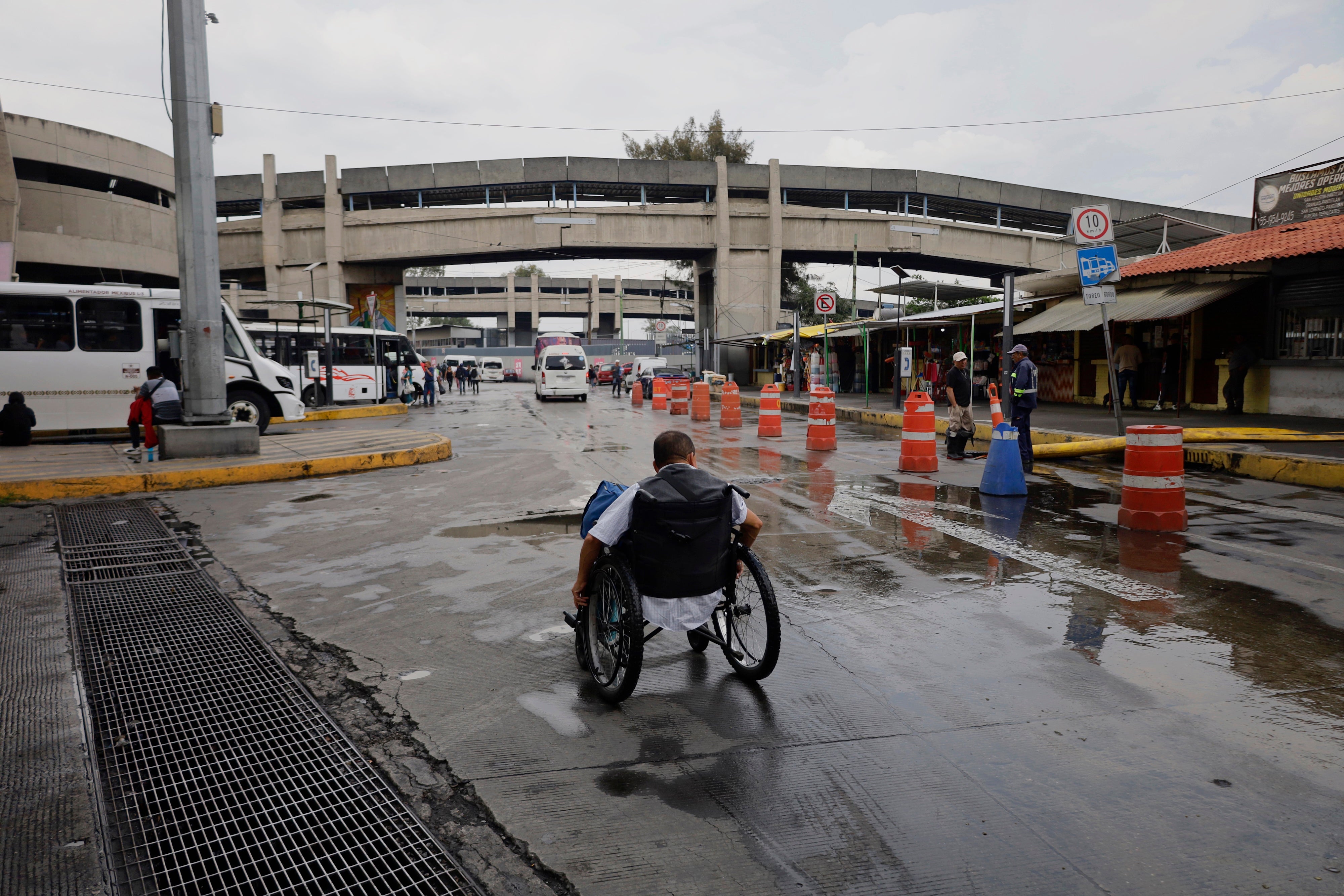 A wheelchair user searches for options to cross an under bridge while dredging work is carried out after a historic heavy rainfall in Mexico City, Mexico, on August 10, 2025.