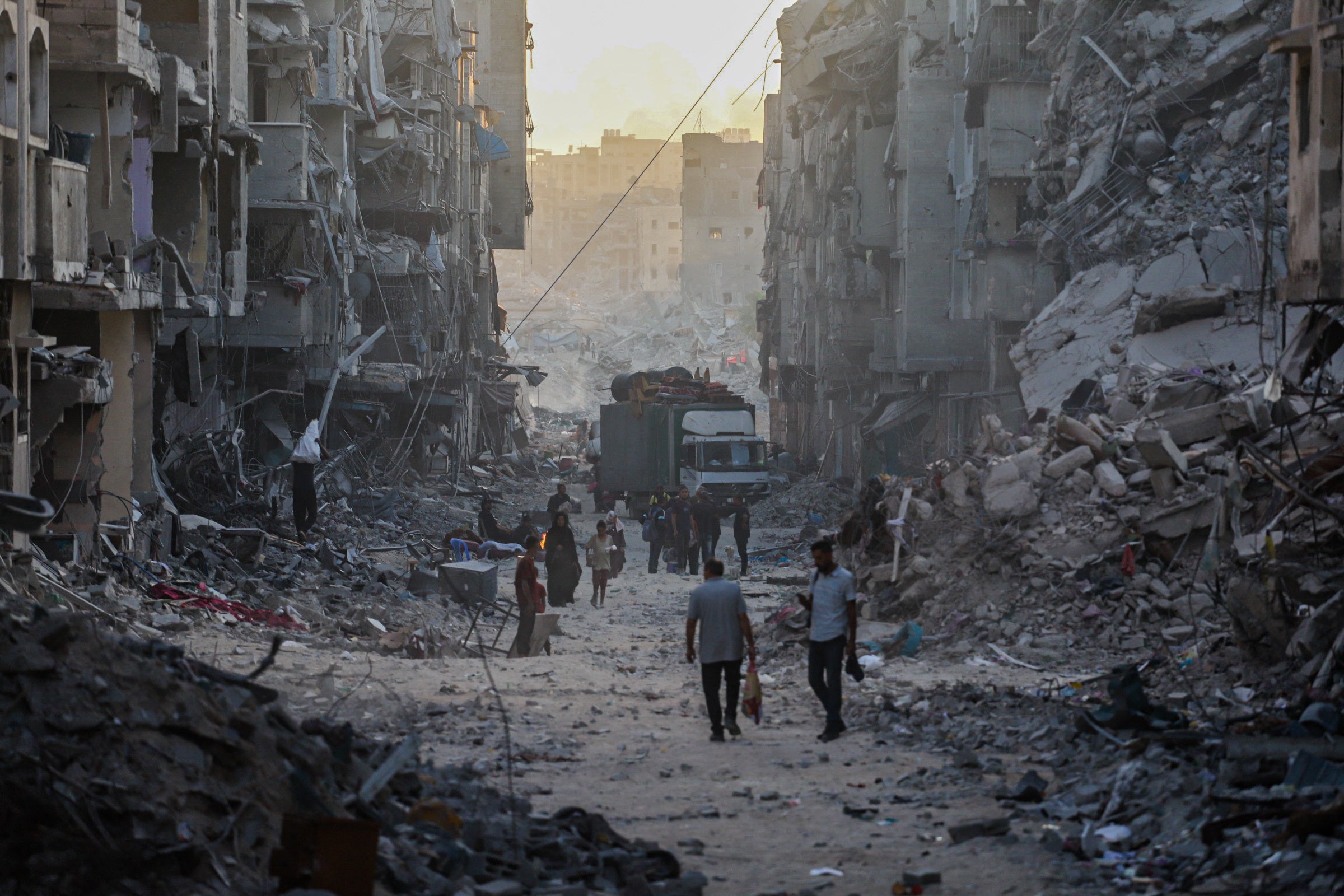 Palestinians walk through the rubble of residential buildings