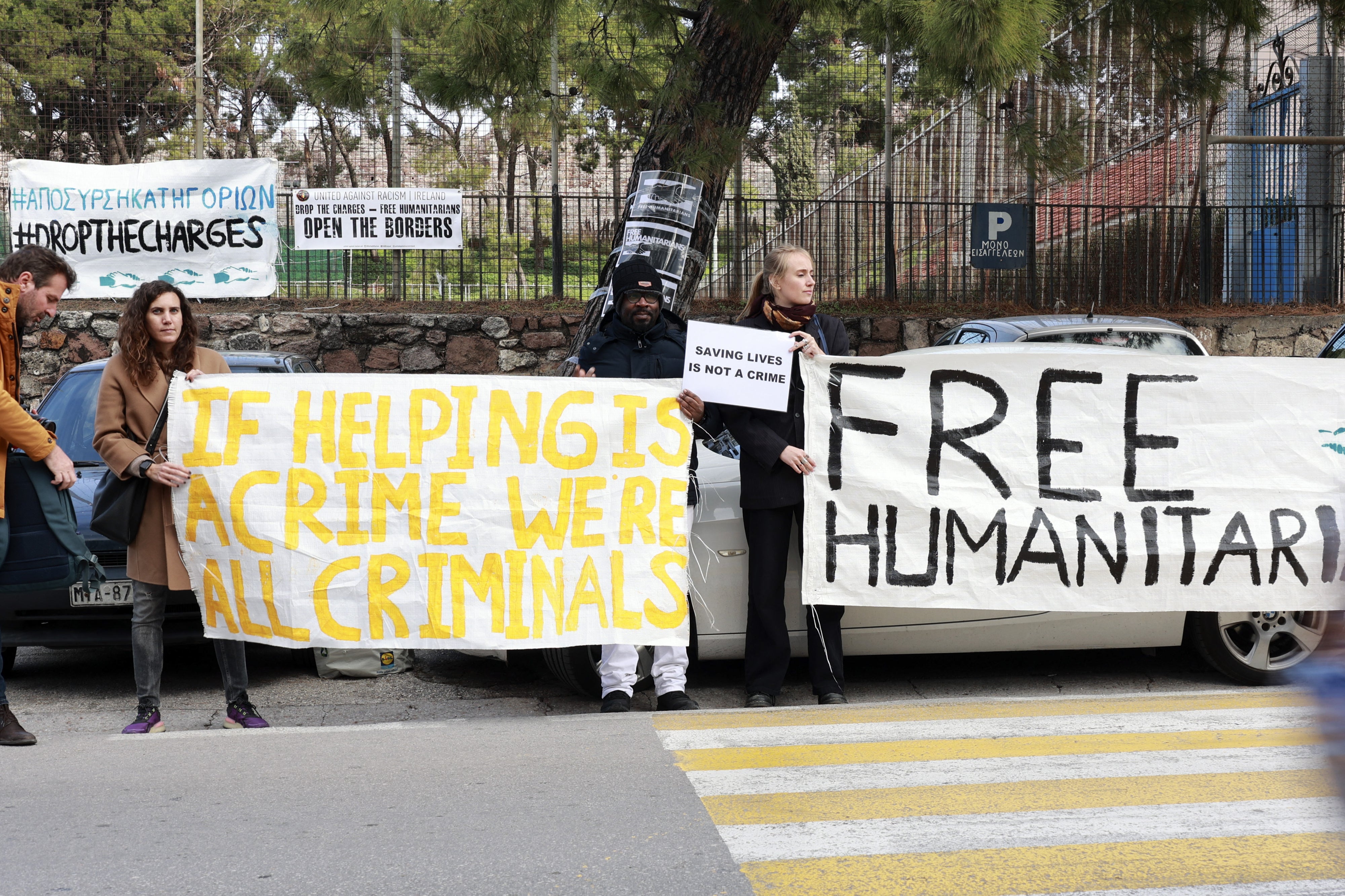 Protesters hold signs outside a Greek court in Mytilene