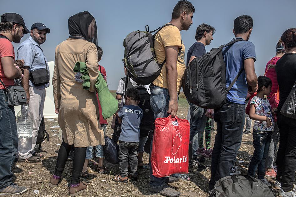 Refugees and asylum seekers, wait in line to be transferred to a transit camp near Röszke, Hungary after crossing the Serbian-Hungarian border. September 1, 2015.