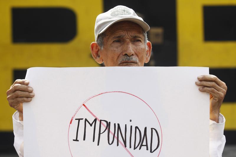 A man holds a banner that reads "impunity", during a protest outside the Special Military Security Unit base in San Salvador, August 24, 2011.