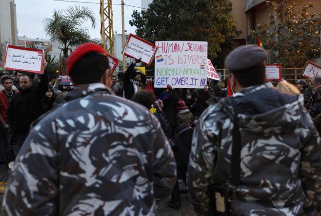 Lebanese police stand guard as protesters carry banners during a sit-in for LGBT rights in Beirut. 