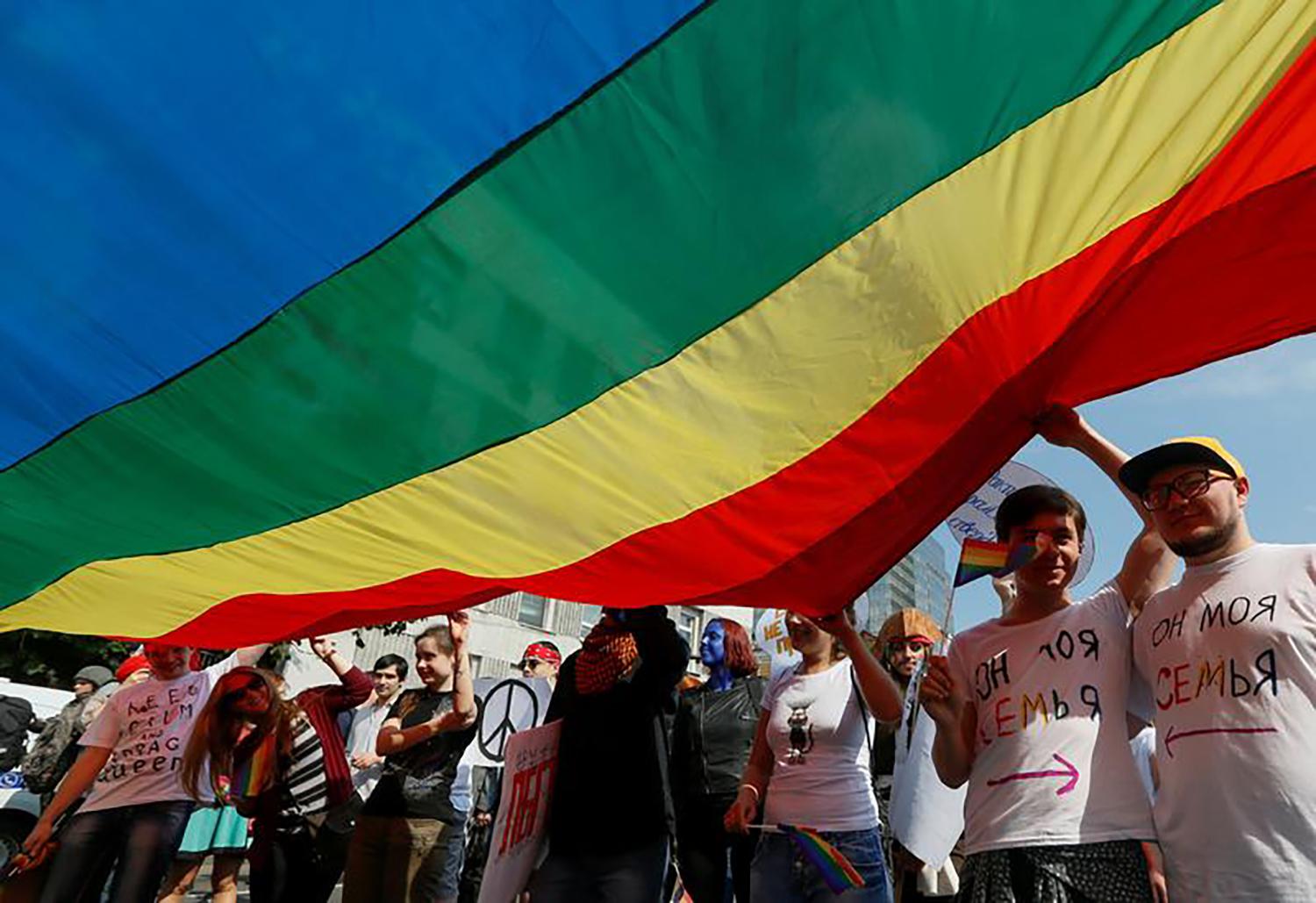 An underside shot of a large rainbow flag being carried by several marchers in the Kiev equality march