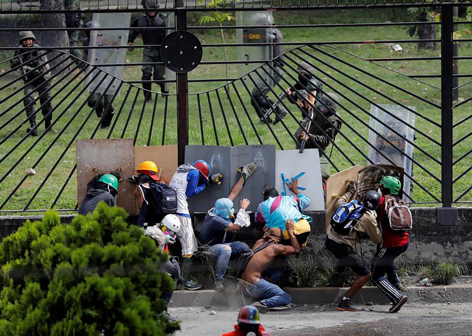 Demonstrators clash with riot security forces at the fence of an air base while rallying against Venezuela's President Nicolas Maduro in Caracas, Venezuela.