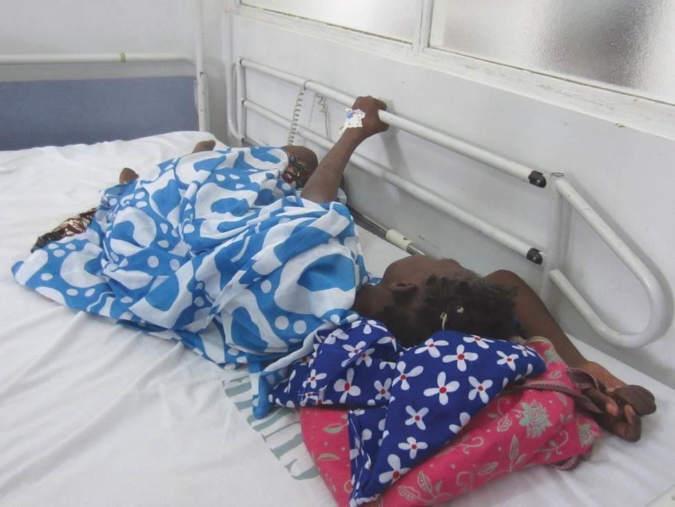 During a morphine shortage, a cancer patient in Dakar cluthes onto the railing of her hospital bed because she is in pain and the medication she needs is unavailable.