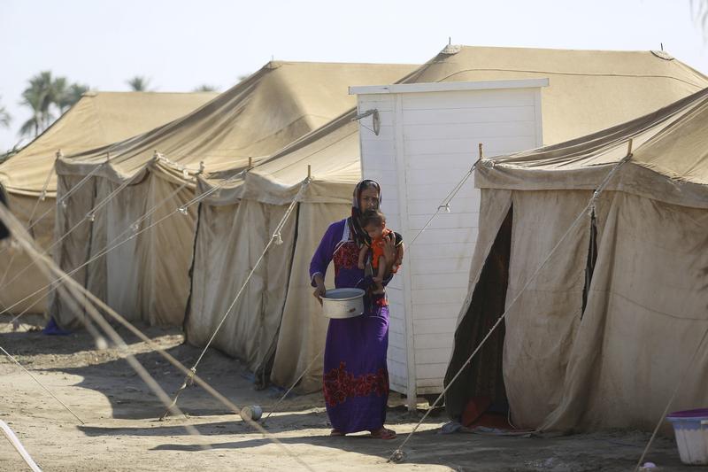 An Iraqi displaced woman, who fled from ISIS violence in Anbar, carries her child at a camp for displaced families camp in Amiriyat al-Fallujah, July 25, 2015. © 2015 