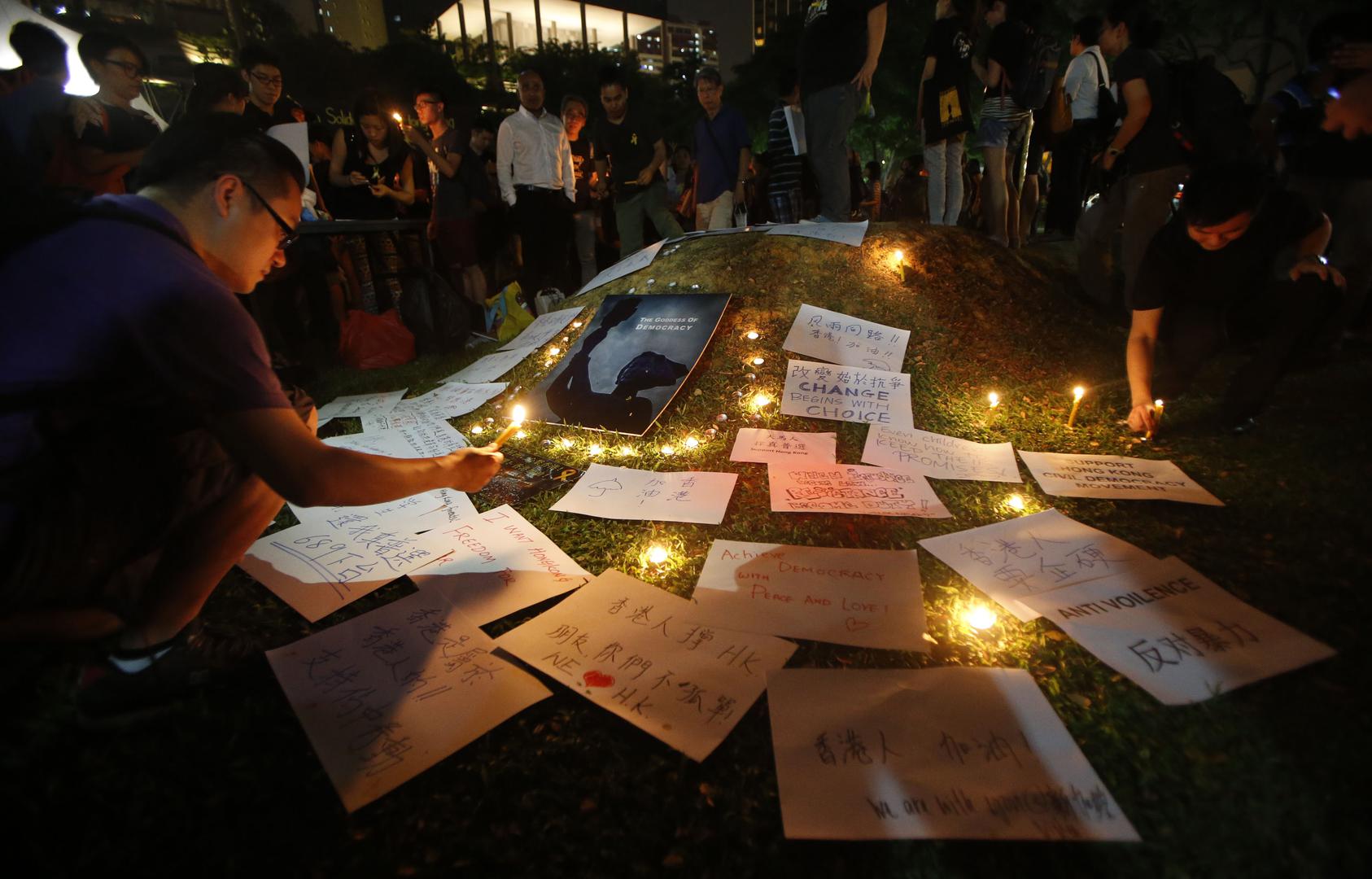 People light candles next to signs at a vigil in solidarity with protesters of the "Occupy Central" movement in Hong Kong, at Speakers' Corner in Hong Lim Park, Singapore, on October 1, 2014. 