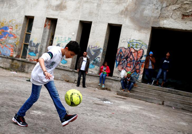 Migrants are seen in front of a dorm destroyed during Bosnian 1992-1995 war, in Bihac, Bosnia and Herzegovina May 11, 2018.