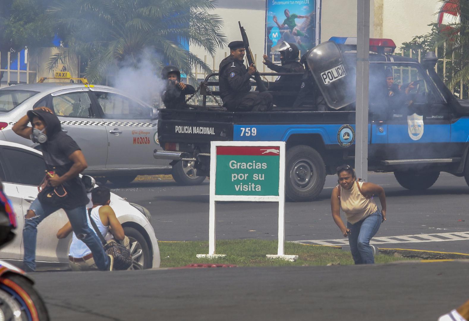 An officer of the National Police shoots at a group of people outside the shopping mall Metrocentro in Managua, Nicaragua, May 28, 2018. 