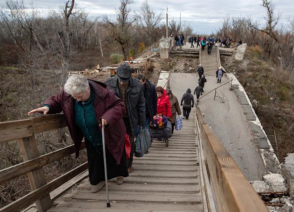 Older people crossing the broken bridge at the Stanytsia Luhanska checkpoint.