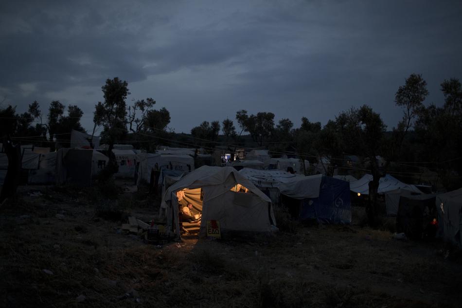 A Syrian man reads inside his tent at a makeshift camp outside Moria on the northeastern Aegean island of Lesbos, Greece.