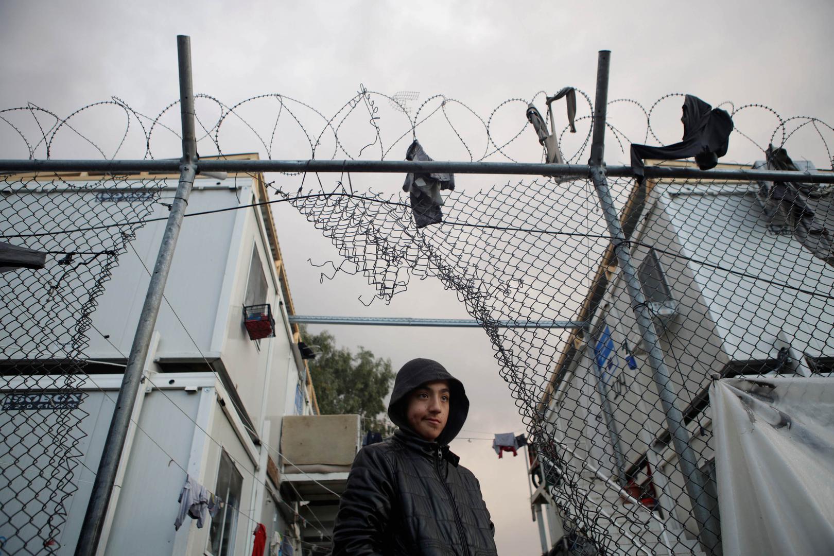 A boy stands next to a hole in the fence of the Moria camp following rainfall, on the island of Lesbos, Greece, November 22, 2019. REUTERS/Elias Marcou