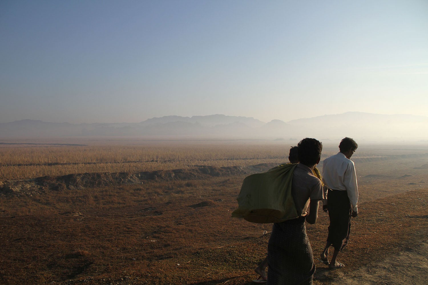 Three people walk along a road close to the surge of fighting between the Arakan Army and Myanmar military in Rakhine State, January 25, 2019.