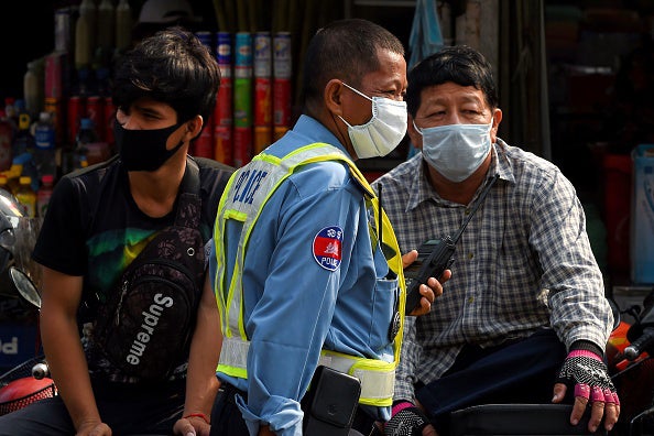 A policeman (center) and others wear face masks as a preventive measure against COVID-19, at a market in Phnom Penh on March 17, 2020.