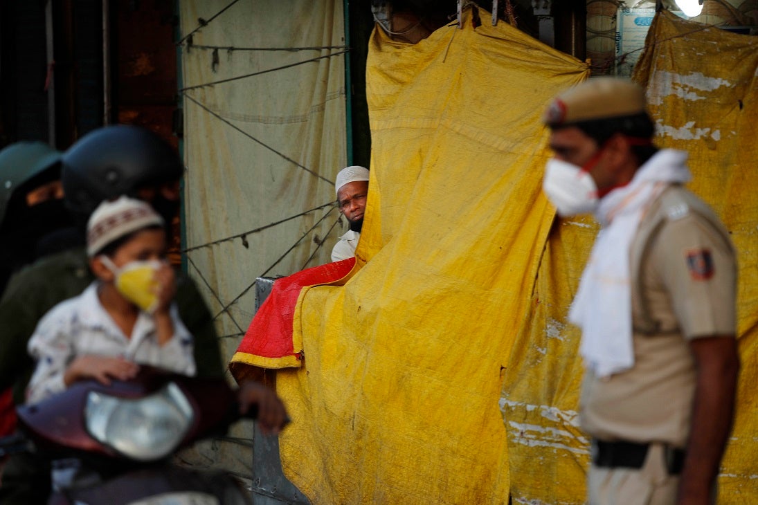 An Indian Muslim watches a policeman instructing a family riding on a scooter on social distancing on the first day of the holy month of Ramadan at the old quarters of New Delhi, India, Saturday, April 25, 2020. 
