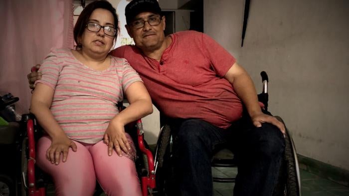 A man and woman in wheelchairs pose for a photo 