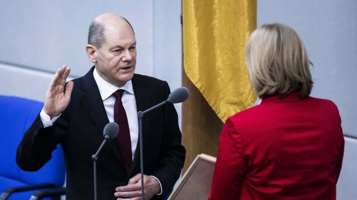 A man wearing a suit raises his right hand