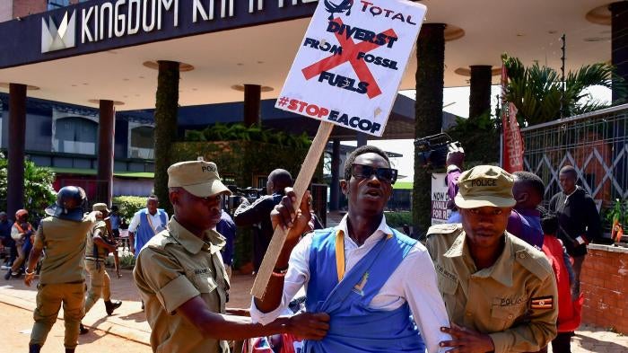 security officials detain a protester holding a placard