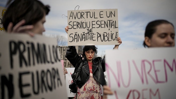 A woman holds a banner that reads "Abortion is an essential public health service" at a rally