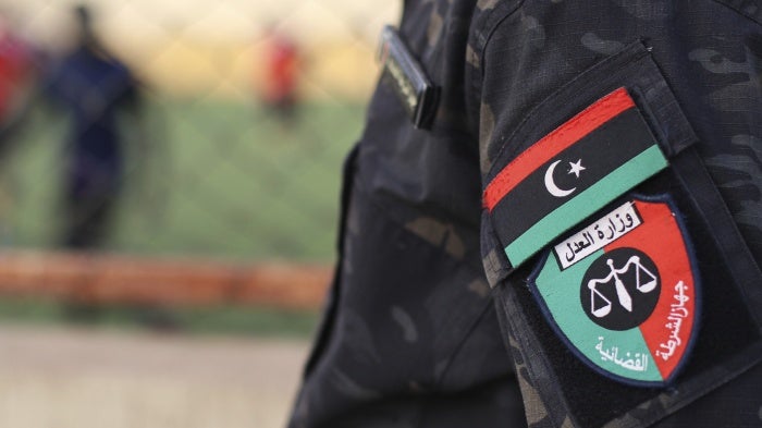 An emblem on the uniform of a judicial police guard standing at a prison