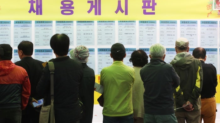 Older people look at a recruitment bulletin board at a job fair