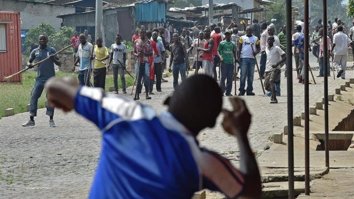 A protestor throwing rocks at members of Imbonerakure.