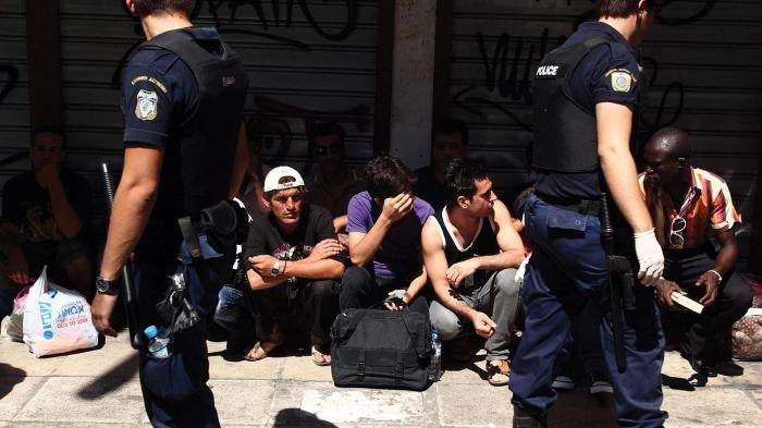 Police detain individuals assumed to be migrants in central Athens, on Sunday, August 5, 2012.