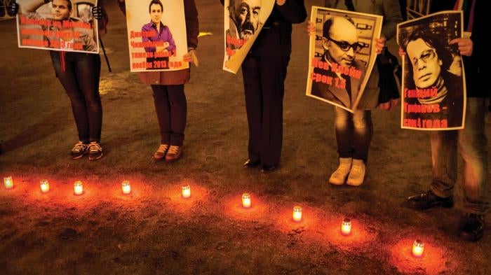 People hold posters depicting victims of homophobic violence at a public event in St. Petersburg.